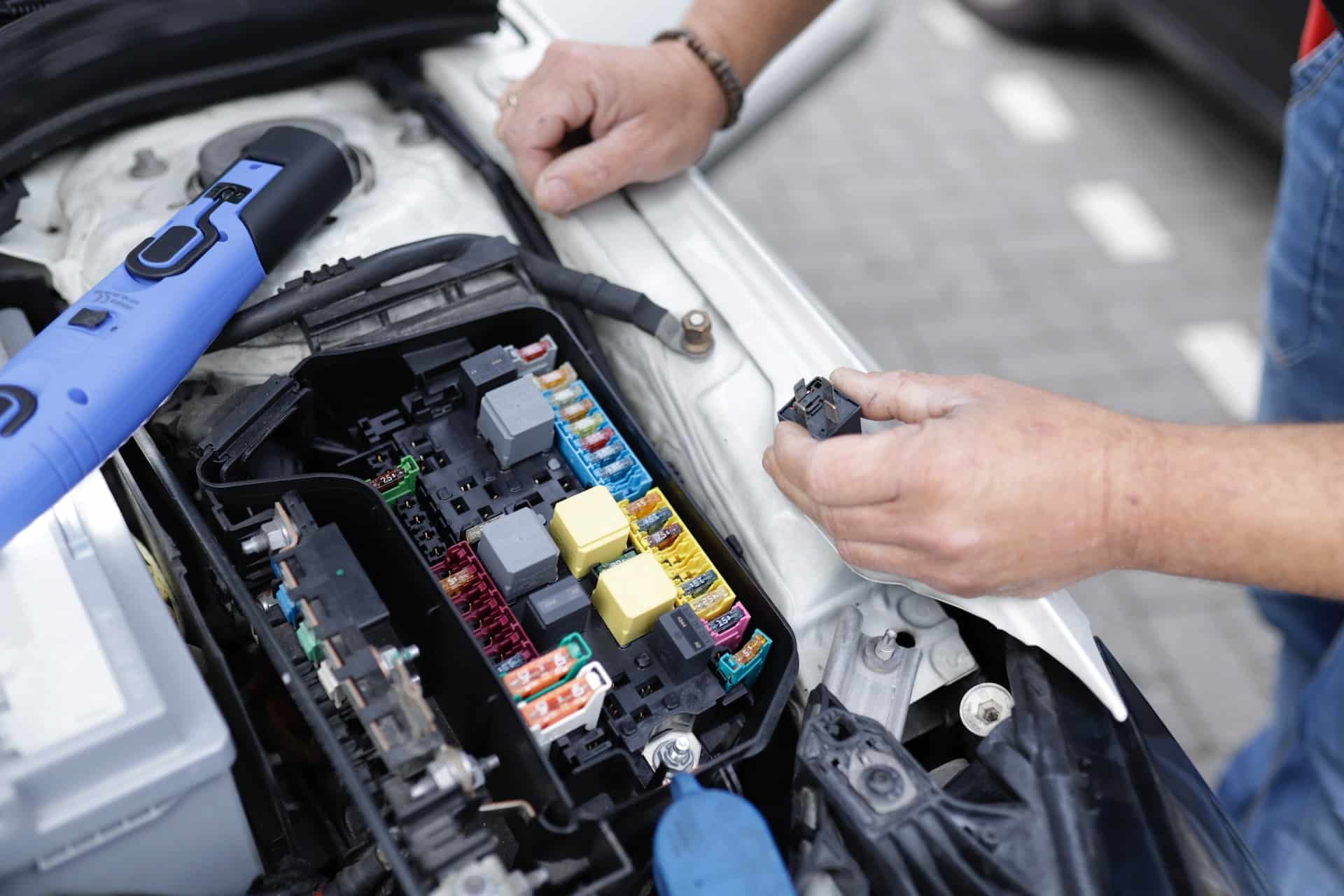an ev technician inspects the fuse box on a vehicle