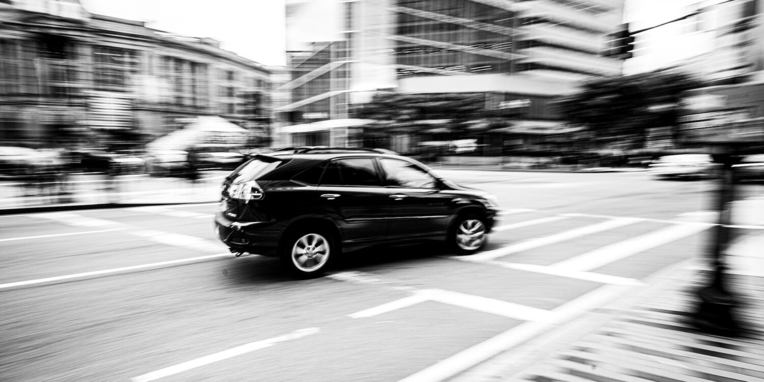 a black and white photo of a Car 极速赛车 at an intersection in a city