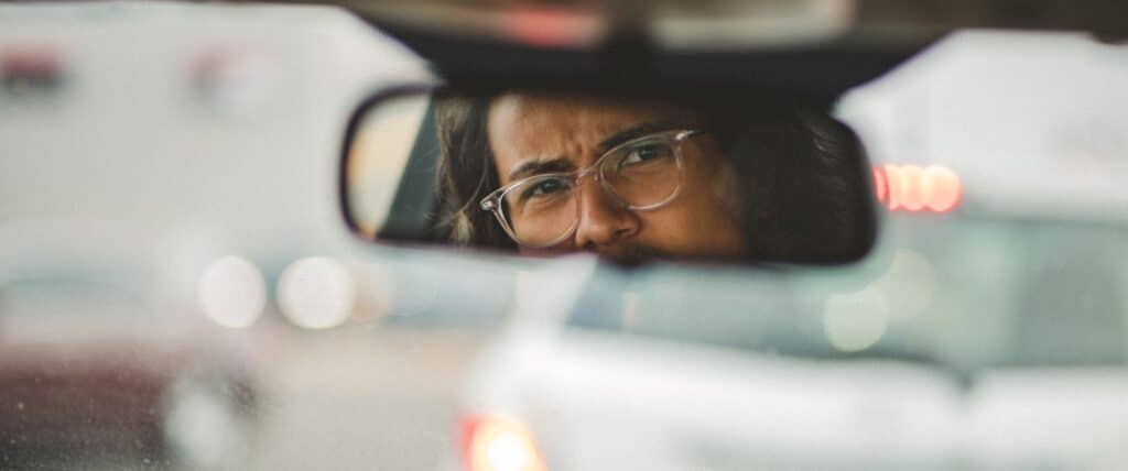 a driver looks angrily into a rear view mirror in a car